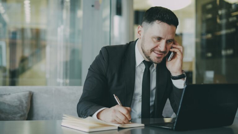 Homem De Terno Falando Ao Telefone Enquanto Escrevia No Caderno AA6sUQaSFZg