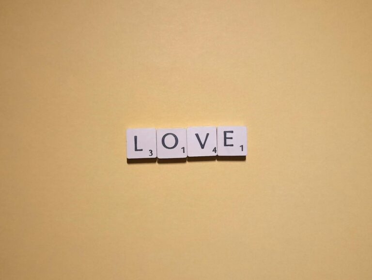 Scrabble tiles spelling 'LOVE' on a warm yellow background, minimalist design.