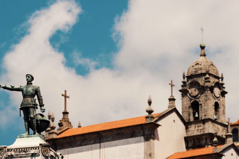 Dramatic view of Porto's historic architecture and iconic statue under a vibrant sky.