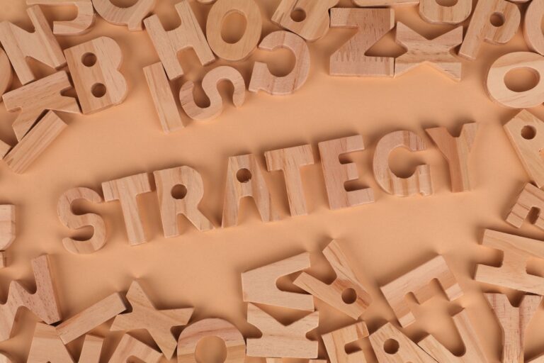 Overhead view of wooden letter blocks spelling 'Strategy' on a soft brown background.