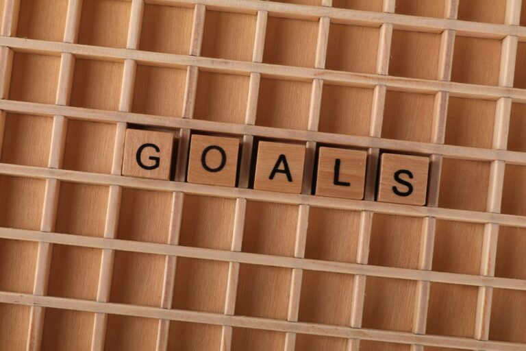 Wooden alphabet tiles spelling 'GOALS' on a grid background, symbolizing aspirations.