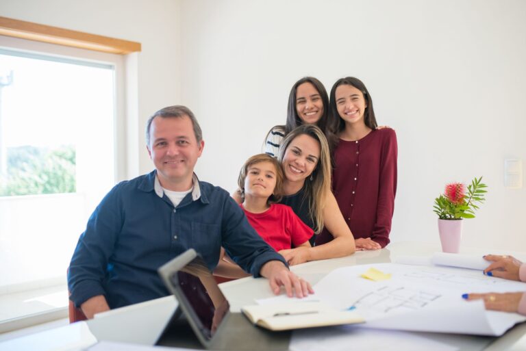 Smiling family at home with architectural plans, embracing warmth and togetherness.
