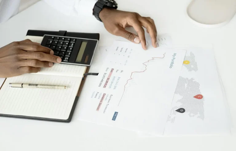 Overhead view of a person analyzing financial documents using a calculator for investment planning.