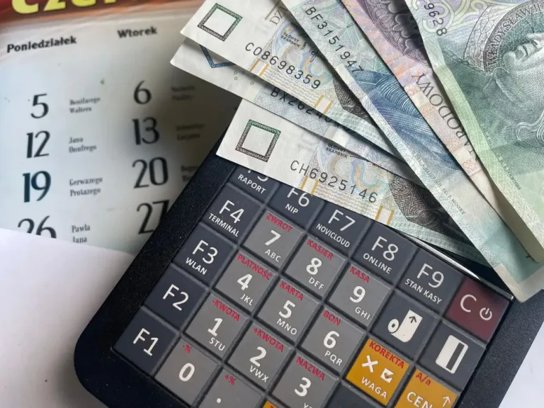 Close-up of Polish Zloty banknotes on a calculator with a calendar in the background.